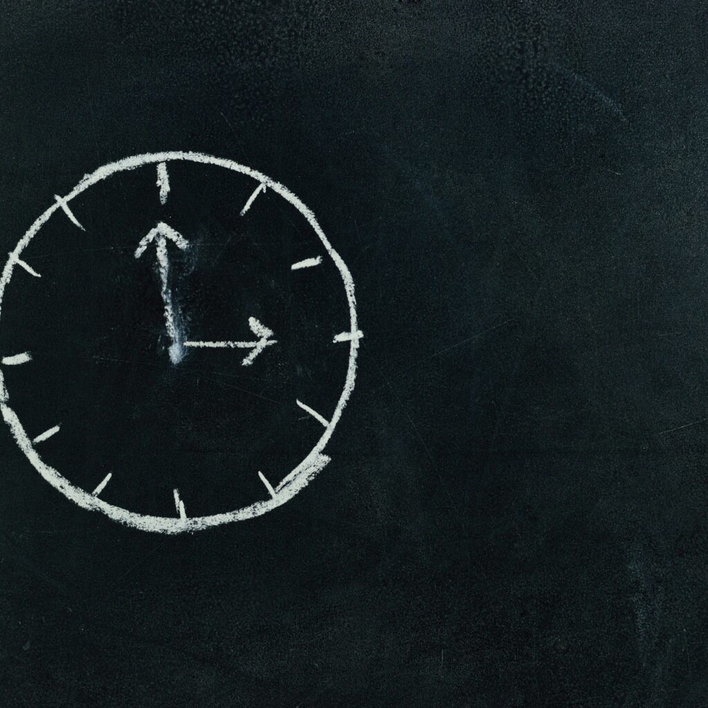 Chalk-drawn clock on a blackboard, symbolizing time and education concepts.